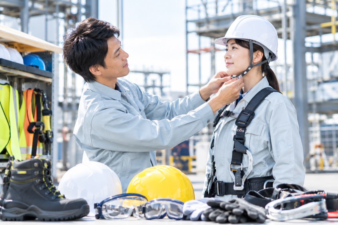 ヘルメットの着用を手伝う作業員と安全保護用品